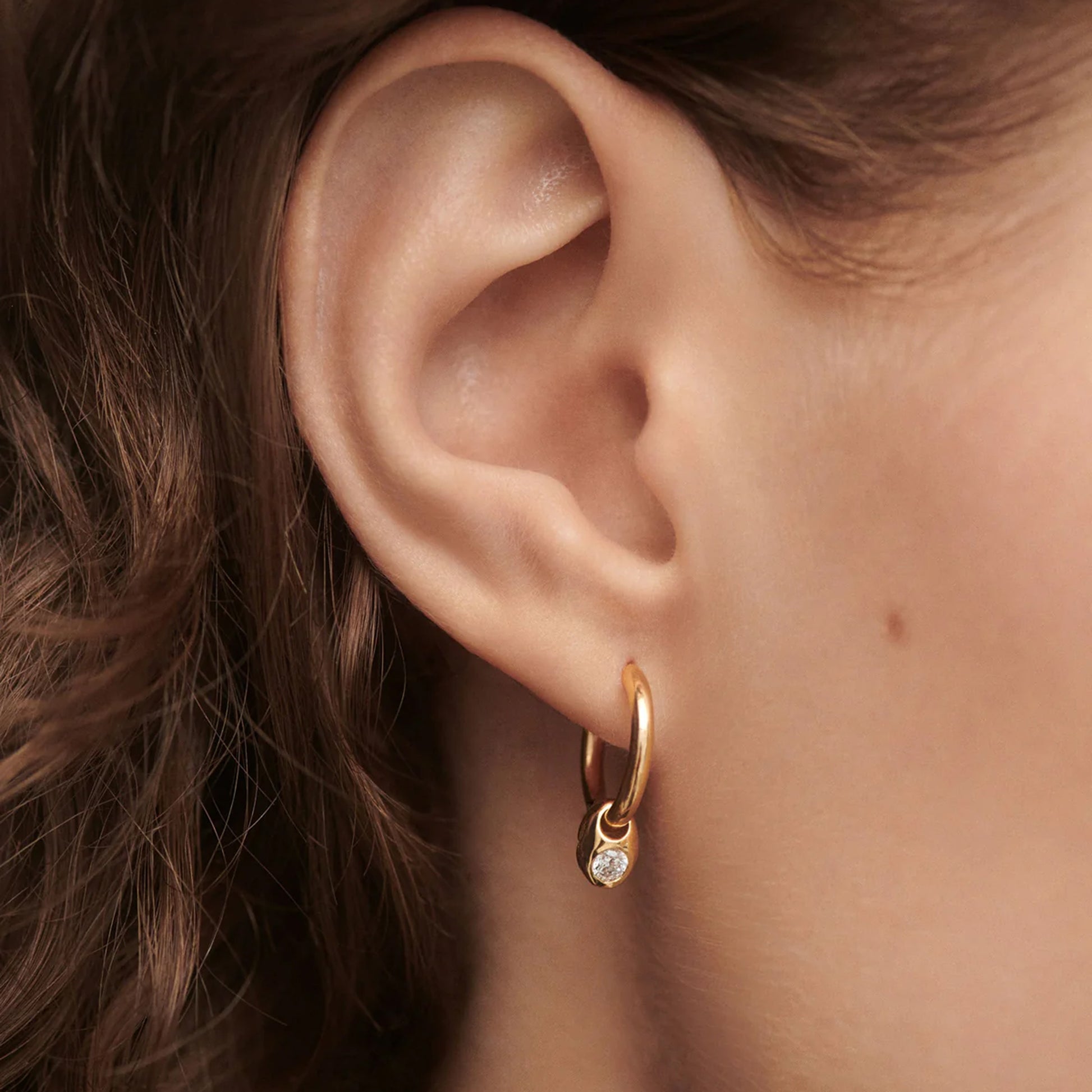 Model wearing PDPALOA 18ct gold plated sterling silver hoop earrings with cz charm