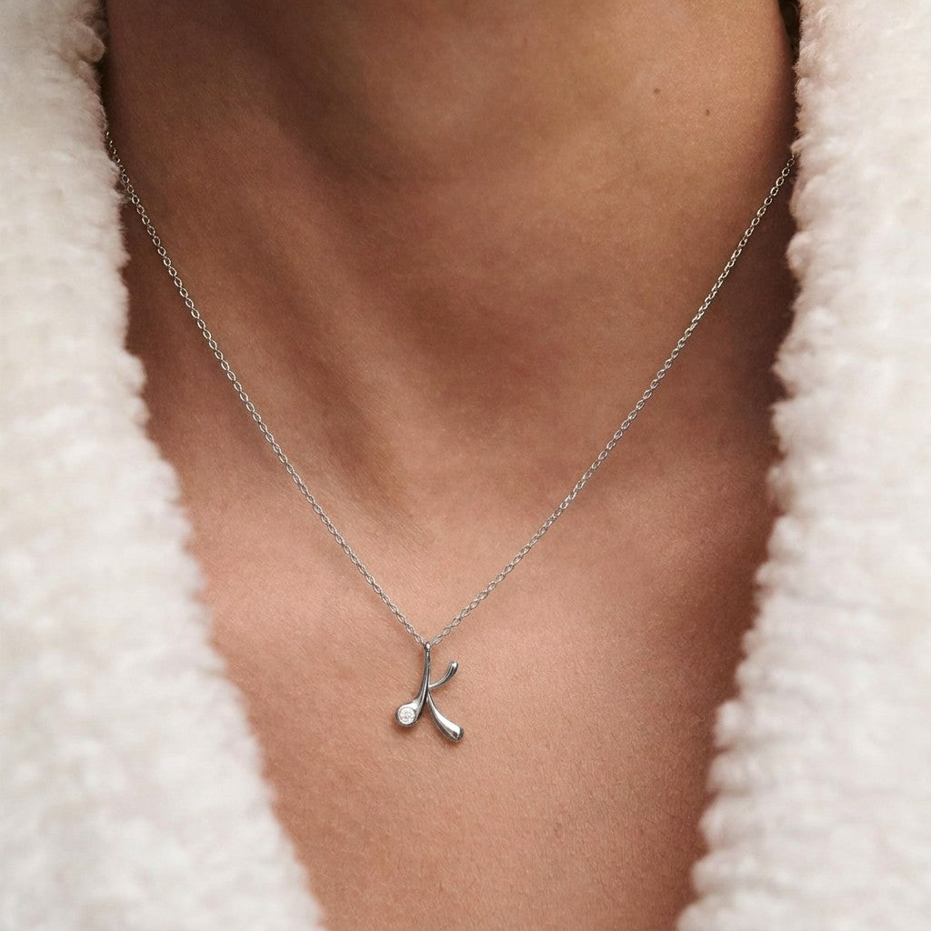 Model wearing a PDPAOLA sterling silver initial K necklace with cz